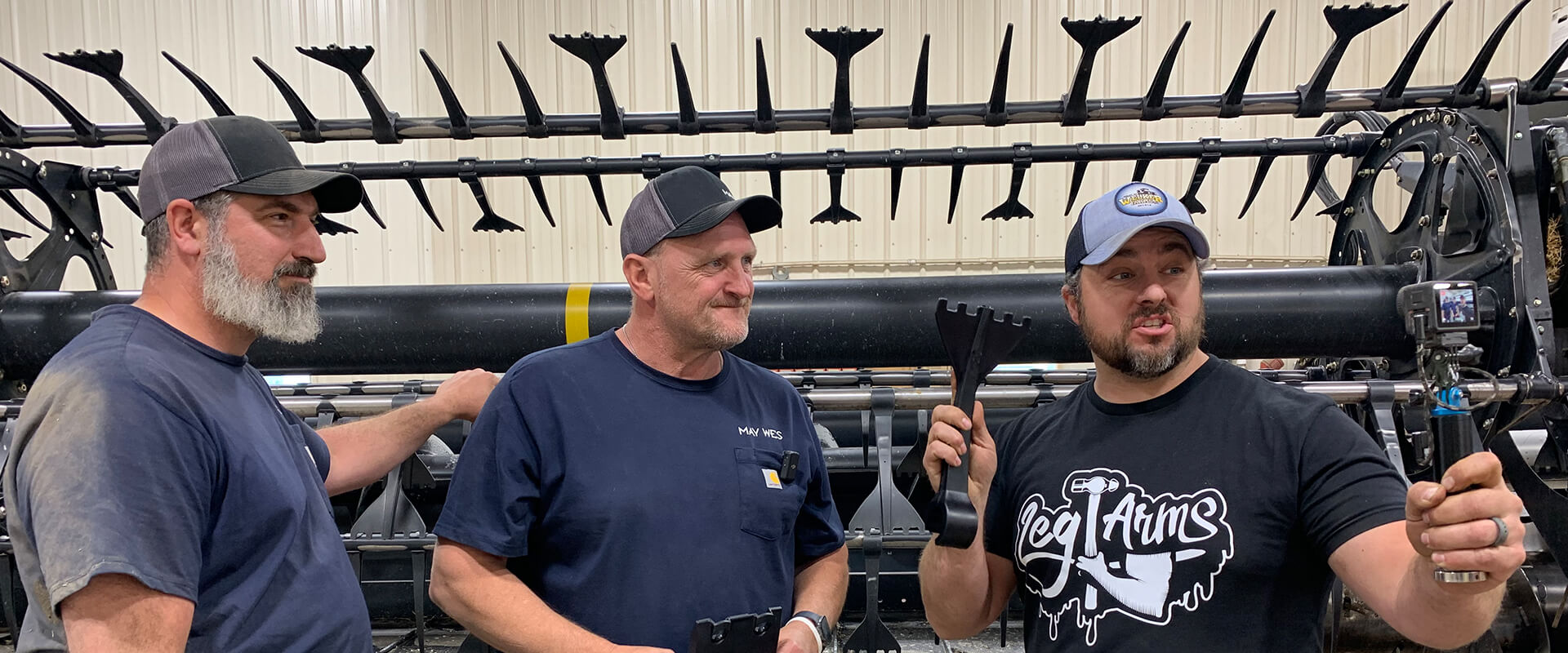 Eric and Matt from May Wes with Scott from Welker Farms standing in front of grain head with May Wes 5-Finger Quick Tines