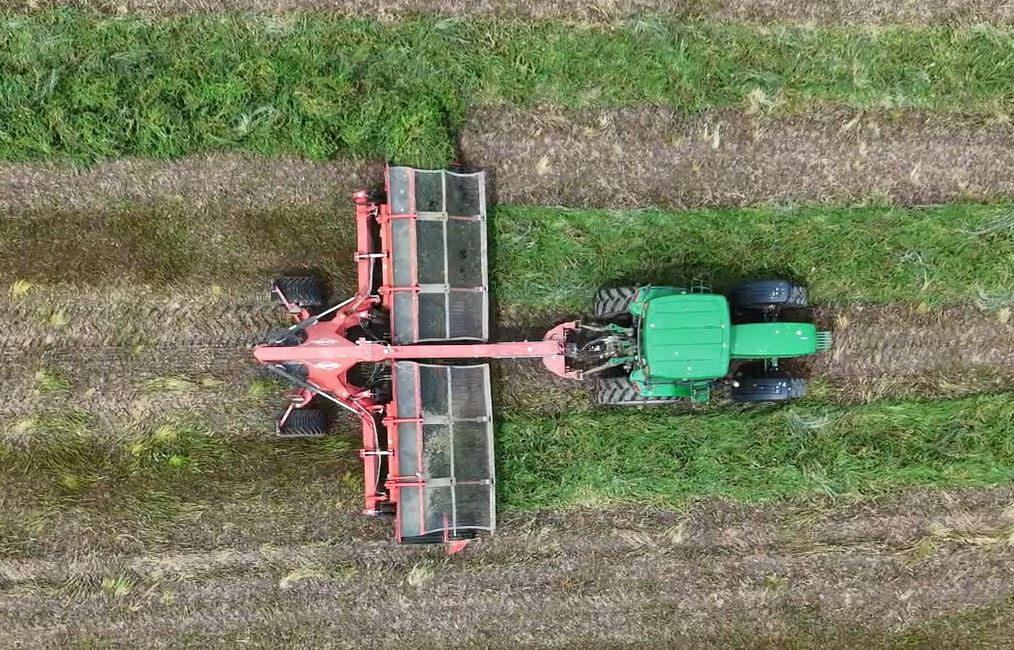 Hay merger in the field with green tractor