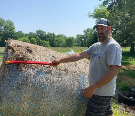 Farmer cutting bale wrap with hay knife