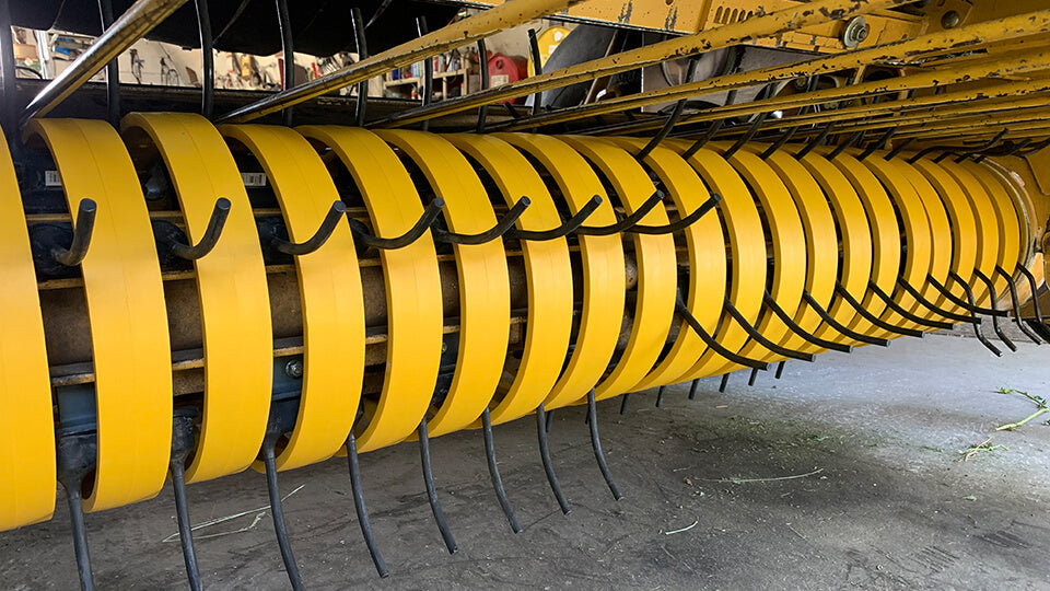 Yellow poly pickup bands and Black Talon rubber baler teeth installed in a Vermeer 605 Super M baler