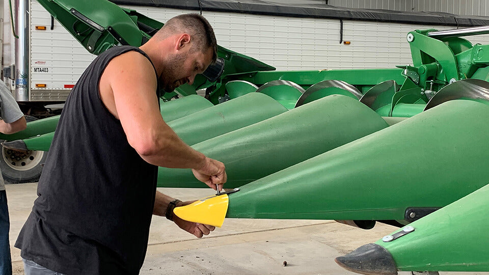 Load video: Zach Johnson, the Millennial Farmer, installing a yellow May Wes Snoot Boot on a John Deere C Series corn head