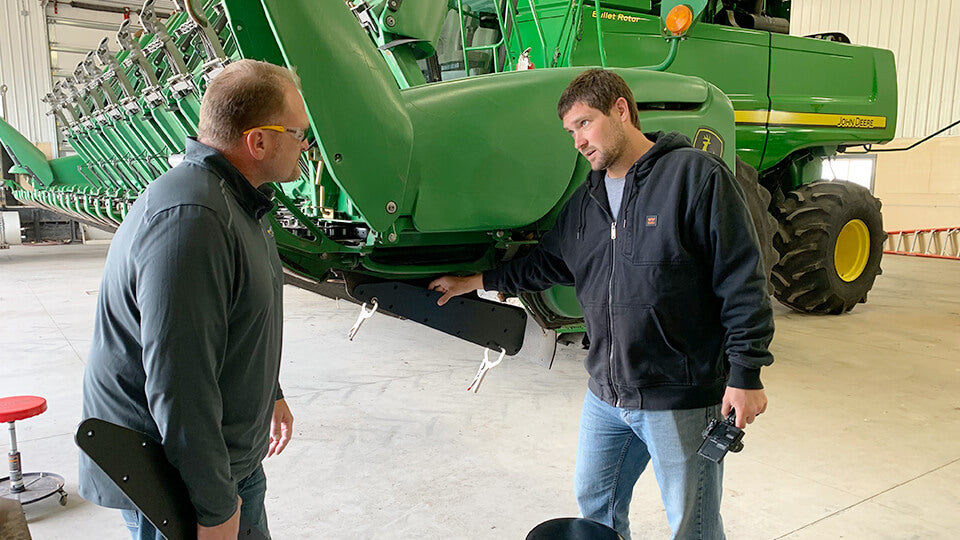 Load video: Eric from May Wes Manufacturing and Zach Johnson the Millennial Farmer installing May Wes Row Divider Shields on a John Deere chopping corn head